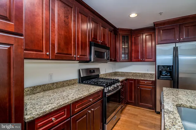 a kitchen with granite countertop wooden cabinets and stainless steel appliances