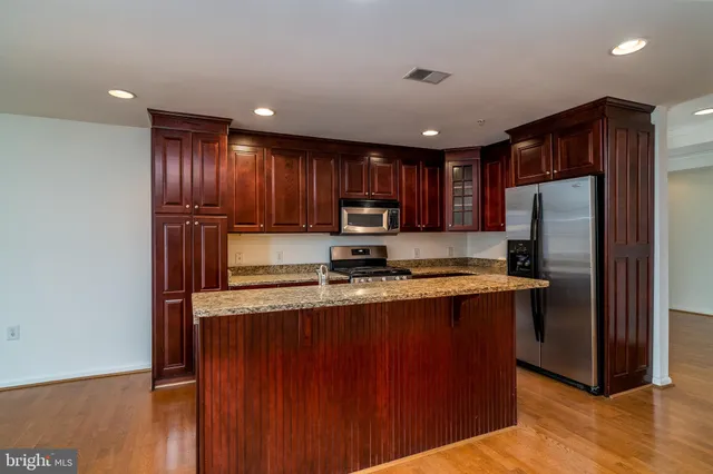a kitchen with kitchen island granite countertop wooden cabinets a refrigerator and a sink