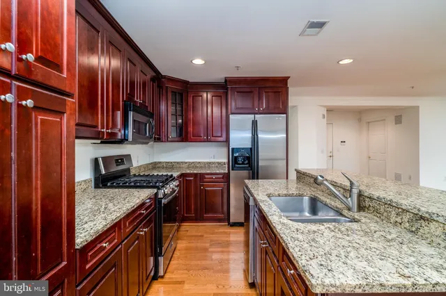 a kitchen with stainless steel appliances granite countertop a sink stove refrigerator and cabinets