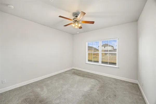 an empty room with chandelier fan and windows