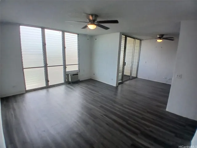 an empty room with wooden floor fan and windows