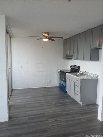 a kitchen with granite countertop a stove cabinets and wooden floor