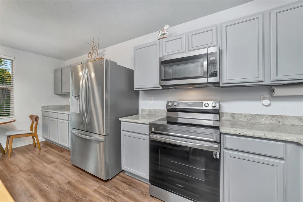 2633 Rockport Lane Little Elm, TX 75068 - Photo 11 of 39 a kitchen with white cabinets and stainless steel appliances