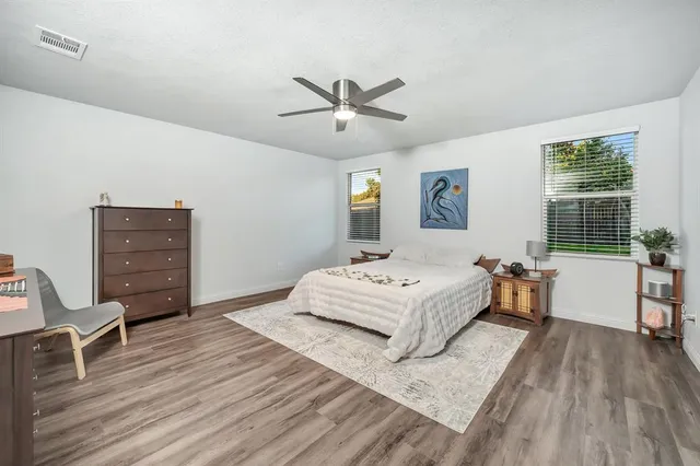 a spacious bedroom with a bed and wooden floor