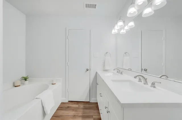 a bathroom with a sink a tub and a mirror