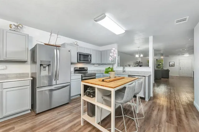 a kitchen with kitchen island stainless steel appliances a sink and refrigerator