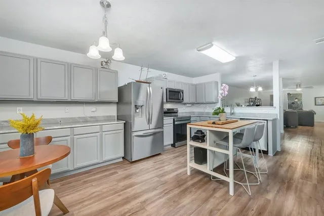 a kitchen with stainless steel appliances kitchen island granite countertop a table chairs and a stove