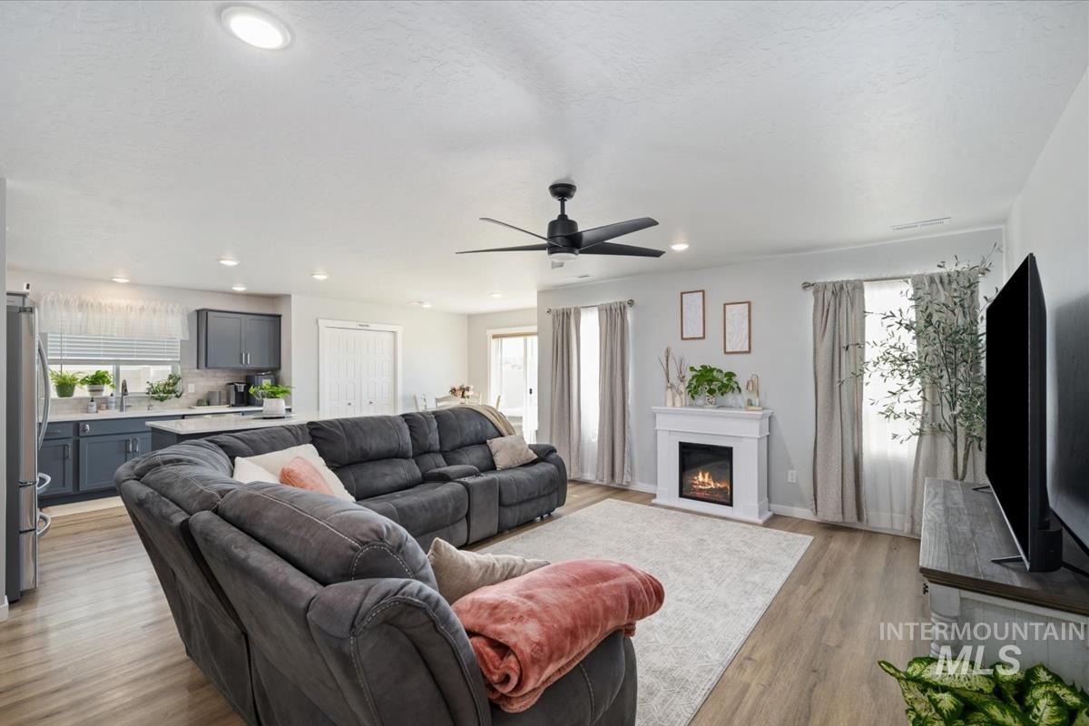 11359 West Langit Street Star, ID 83669 - Photo 24 of 39 Living room with light wood-type flooring, a glass covered fireplace, a ceiling fan, and recessed lighting