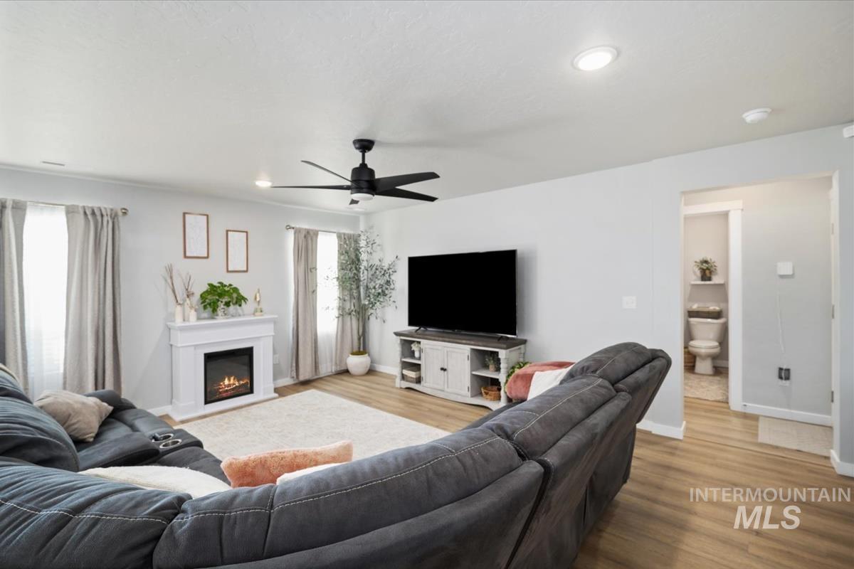 11359 West Langit Street Star, ID 83669 - Photo 25 of 39 Living room featuring light wood-style flooring, a ceiling fan, a lit fireplace, and recessed lighting