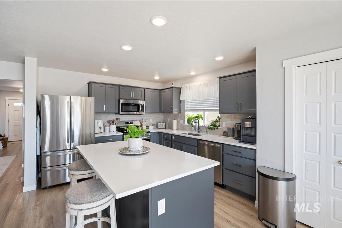11359 West Langit Street Star, ID 83669 - Photo 6 of 39 Kitchen featuring stainless steel appliances, a kitchen island, a breakfast bar area, light wood finished floors, and gray cabinets