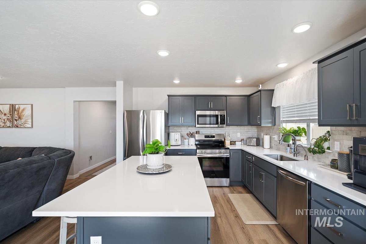 11359 West Langit Street Star, ID 83669 - Photo 39 of 39 Kitchen featuring open floor plan, stainless steel appliances, a center island, light wood-style floors, and light stone countertops