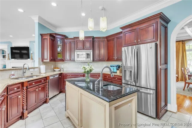 a kitchen with stainless steel appliances granite countertop a refrigerator a sink dishwasher a stove with wooden cabinets and floor