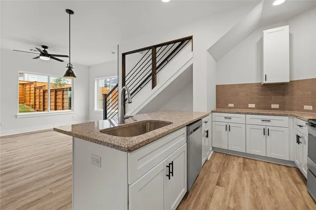 a kitchen with granite countertop a sink stove and cabinets