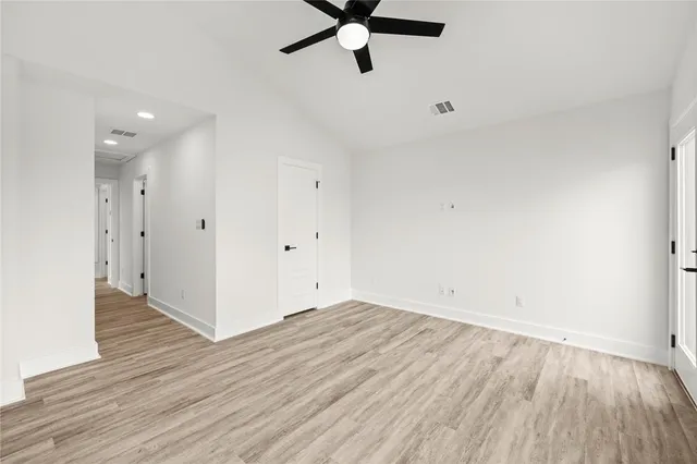 an empty room with wooden floor and a ceiling fan