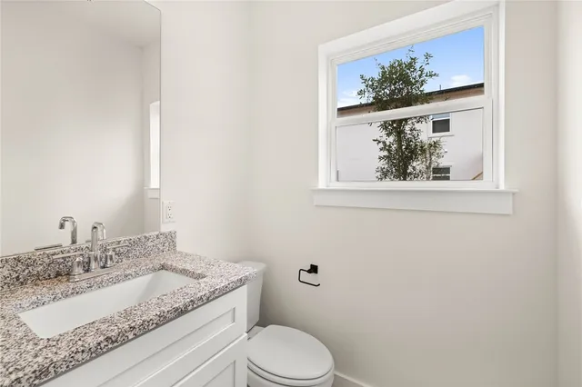 a bathroom with a granite countertop sink mirror vanity and toilet