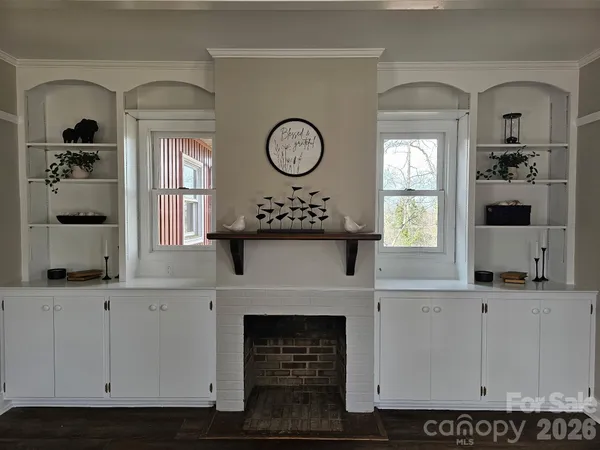 an empty room with wooden floor a fireplace and windows