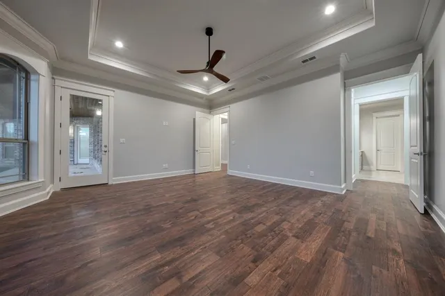 a view of an empty room with wooden floor and a ceiling fan