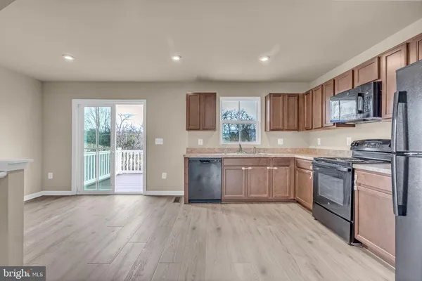 a kitchen with granite countertop wooden floors a stove a sink and a window