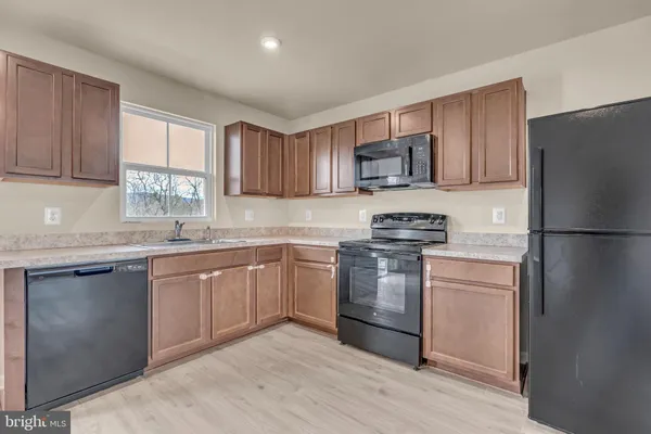 a kitchen with granite countertop a refrigerator stove top oven and sink