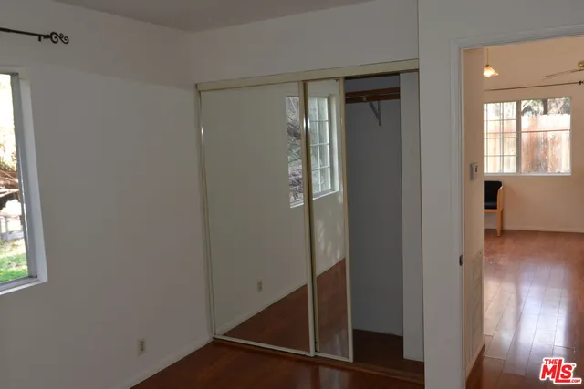 a view of hallway with window and wooden floor