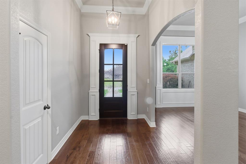 7765 Hickory Spring Lane Tyler, TX 75703 - Photo 5 of 38 Entryway featuring dark wood-finish flooring, a glass-paned front door, white trim, a decorative ceiling light fixture, and an arched doorway