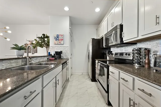 a kitchen with stainless steel appliances granite countertop a sink a stove and a refrigerator