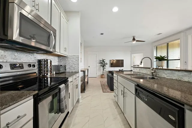 a kitchen with stainless steel appliances granite countertop a stove a sink and a microwave