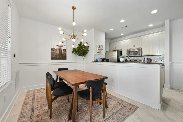 a kitchen with stainless steel appliances kitchen island granite countertop a dining table chairs and a refrigerator