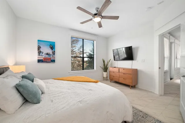 a bedroom with a bed flat screen tv and a window
