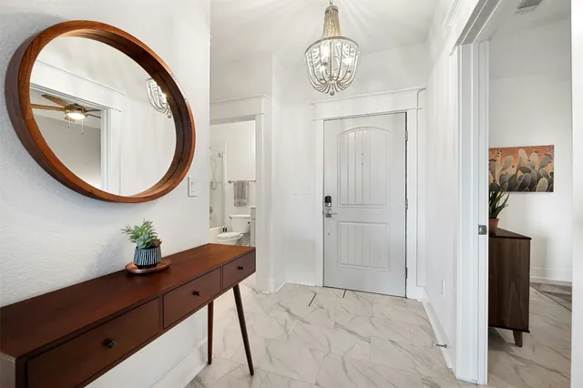 a view of a hallway with front door wooden floor and a chandelier