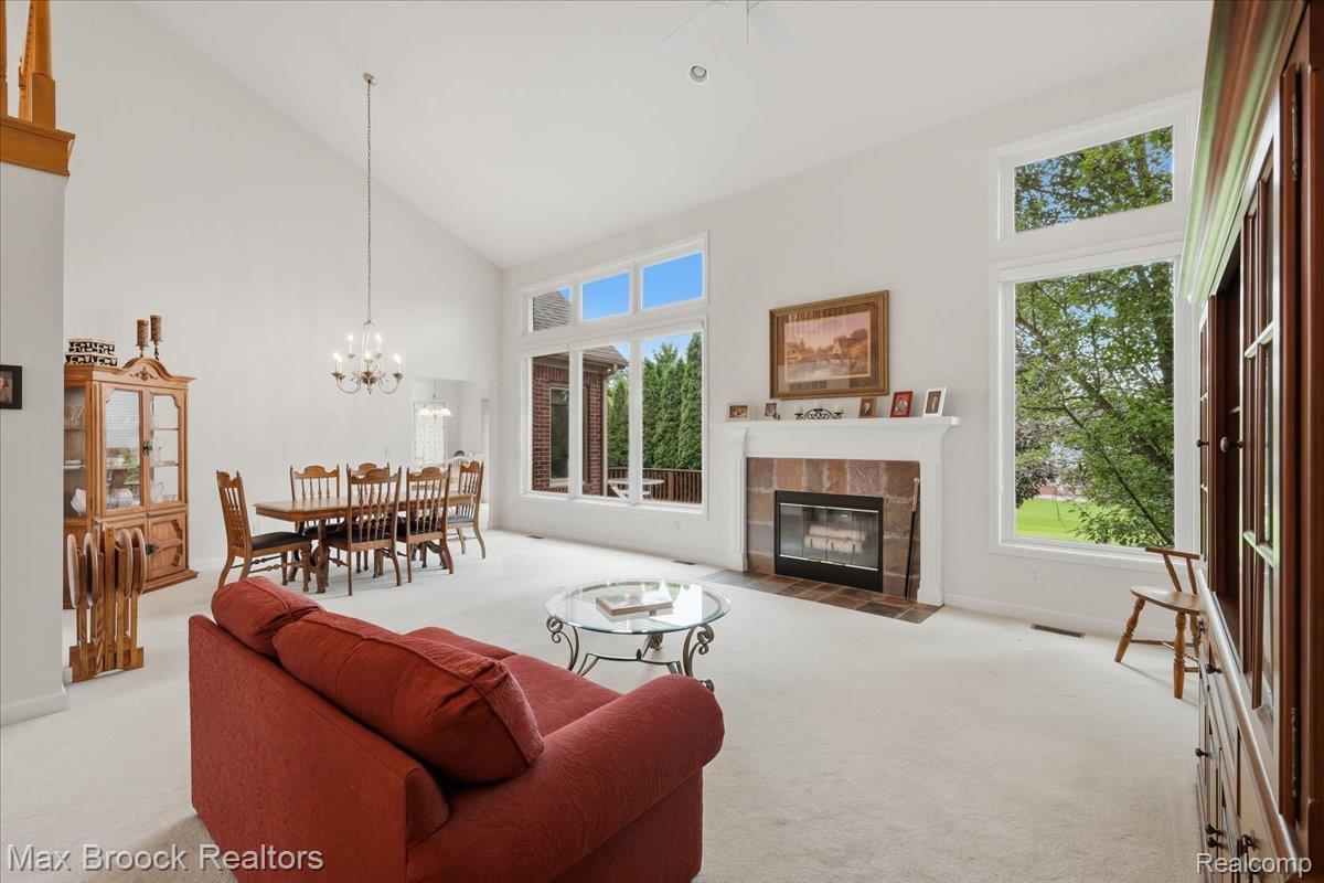1731 Rico Road Commerce Township, MI 48382 - Photo 11 of 48 Vaulted ceiling with an elegant chandelier, expansive windows, and a fireplace featuring a stone surround and white mantel