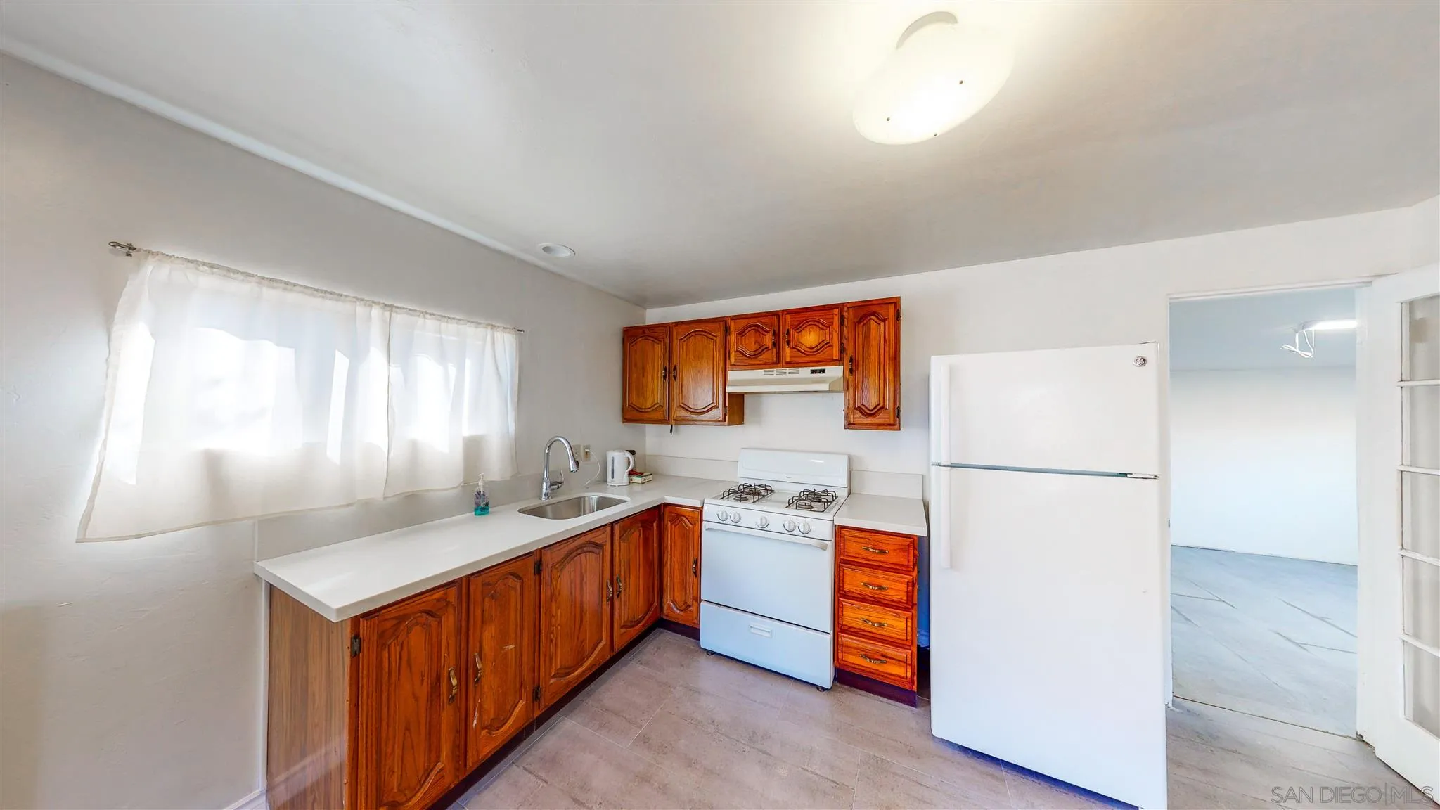 9957 Sierra Madre Road Spring Valley, CA 91977 - Photo 36 of 46 a kitchen with stainless steel appliances a refrigerator a sink a stove a refrigerator white cabinets and wooden floor