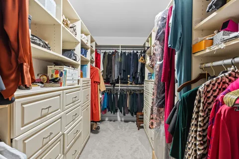 a view of walk in closet with clothes and shoes