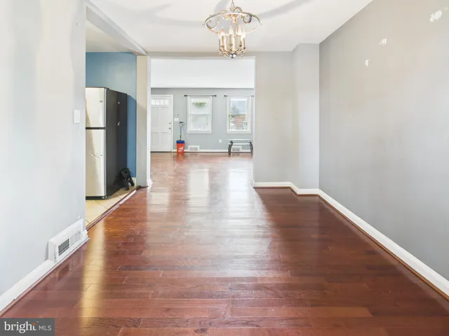 a view of a hallway with wooden floor and a kitchen