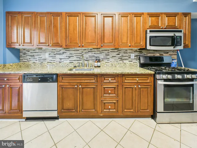 a kitchen with granite countertop a stove top oven microwave and cabinets