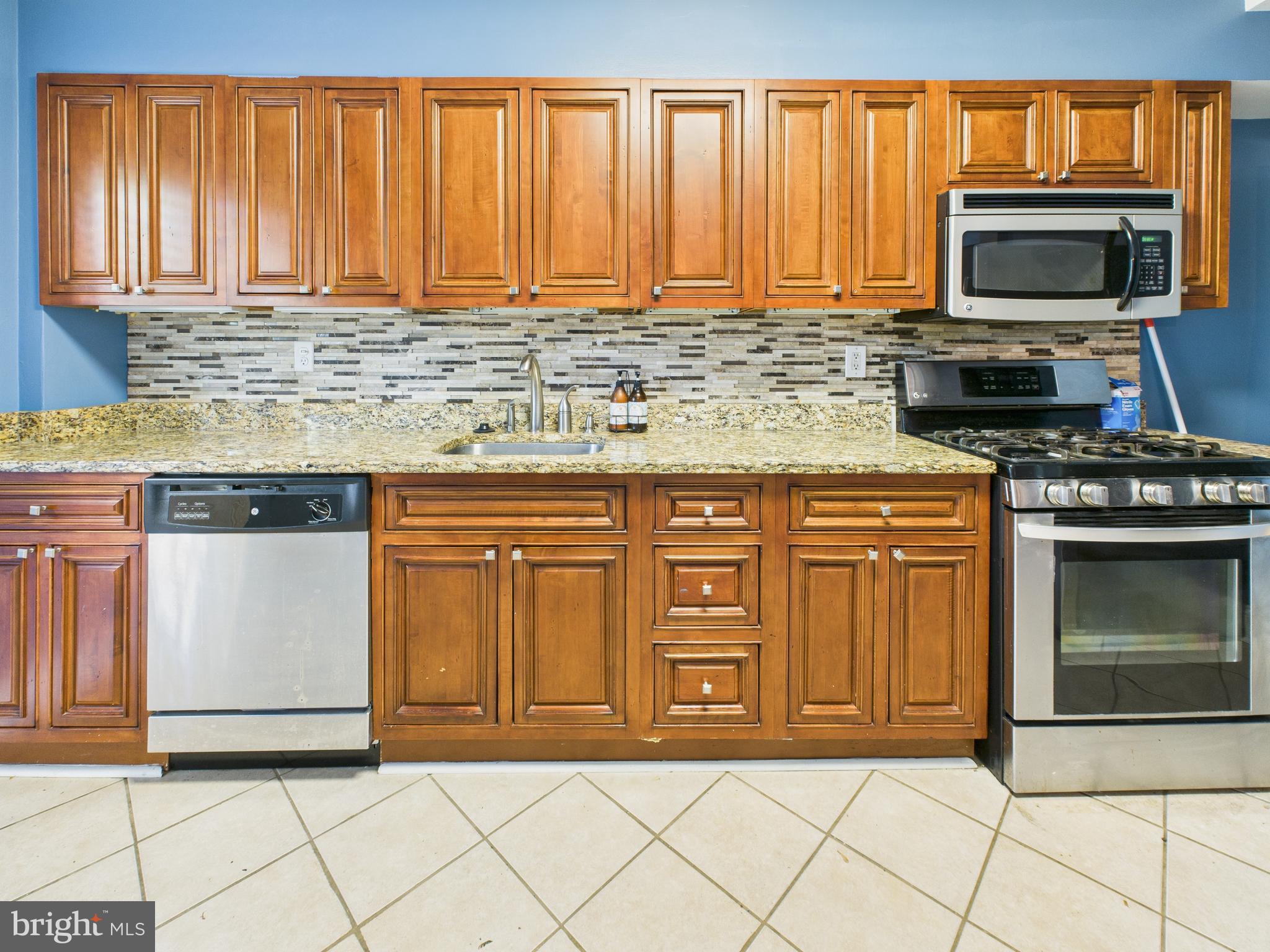1206 Cedarcroft Road Baltimore, MD 21239 - Photo 7 of 29 a kitchen with granite countertop a stove top oven microwave and cabinets