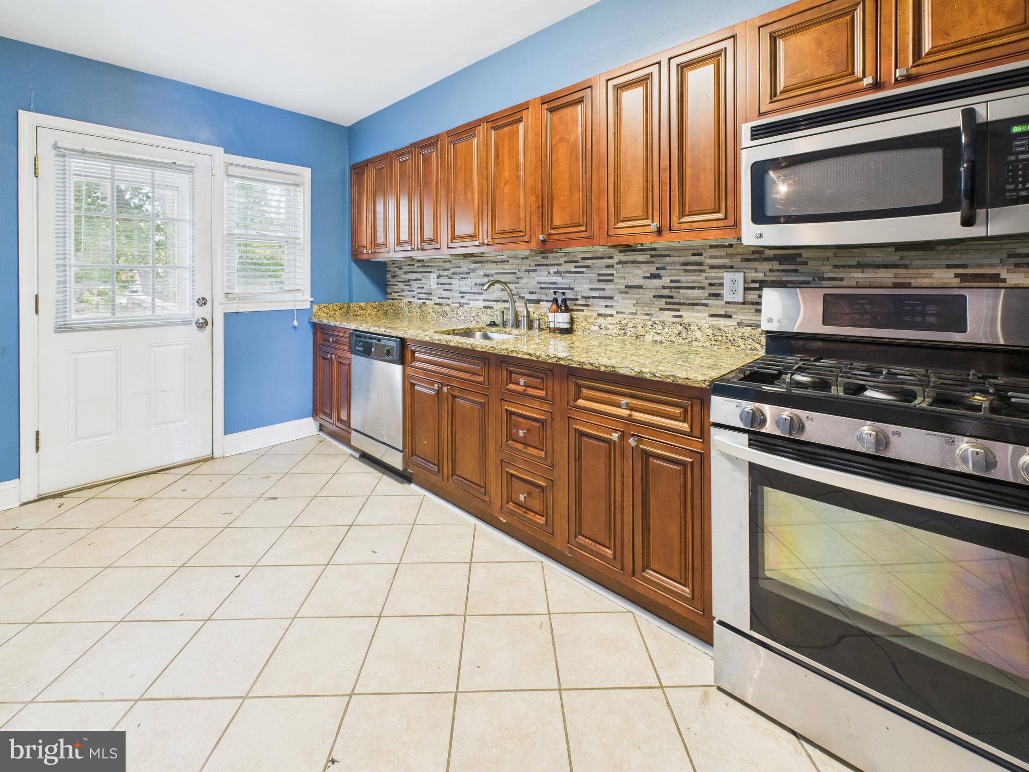 1206 Cedarcroft Road Baltimore, MD 21239 - Photo 9 of 29 a kitchen with stainless steel appliances granite countertop a stove a sink and a microwave