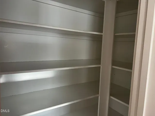 an empty room with wooden floor fireplace and windows