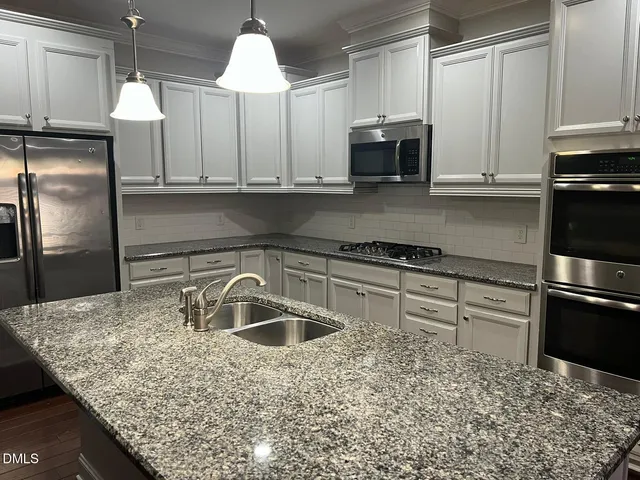a kitchen with kitchen island granite countertop a sink and a stove