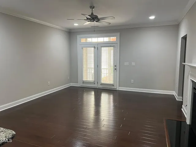 a view of an empty room with wooden floor fireplace and a window