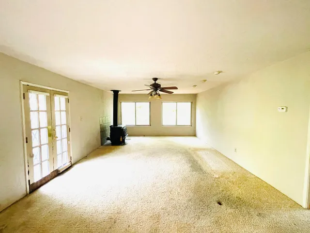 a view of a big room with windows and chandelier fan