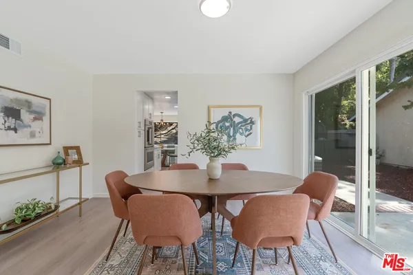 a kitchen with stainless steel appliances a white wooden cabinets a stove a dining table and chairs