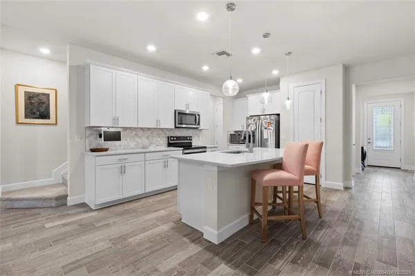 a large white kitchen with lots of counter space and chandelier