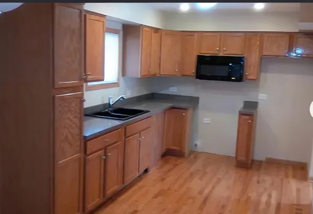 a kitchen with stainless steel appliances a stove a microwave and a hard wood floor