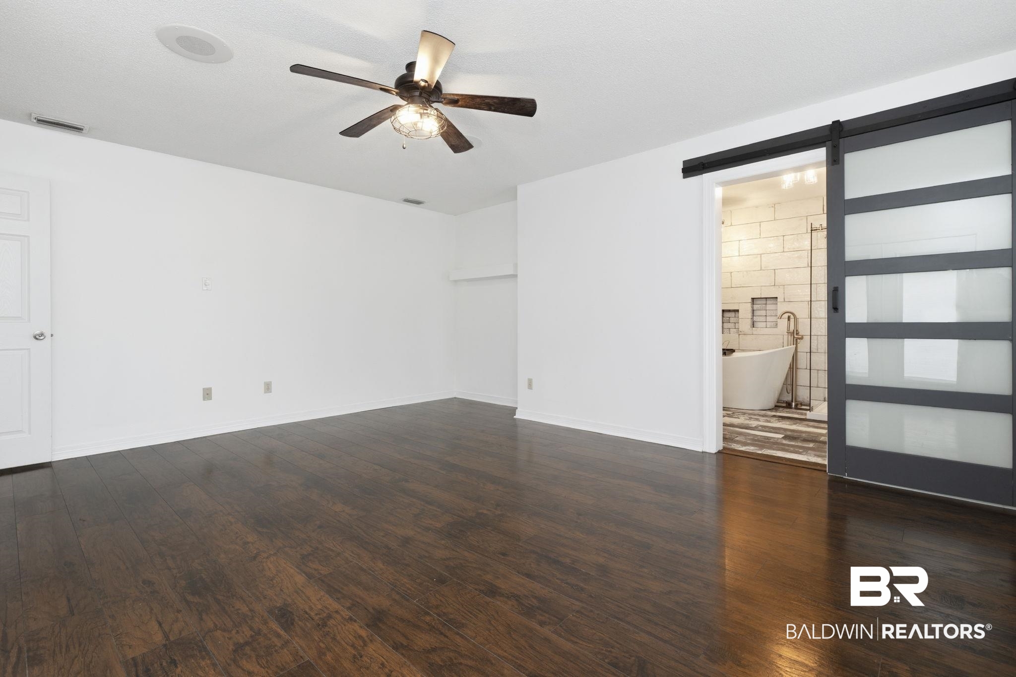 10670 Jeff Hamilton Road Mobile, AL 36695 - Photo 33 of 43 Empty room with a barn door, a ceiling fan, and dark wood-style floors