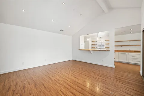 a view of kitchen and empty room with wooden floor and fan