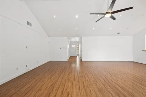 a view of an empty room with wooden floor and a fireplace