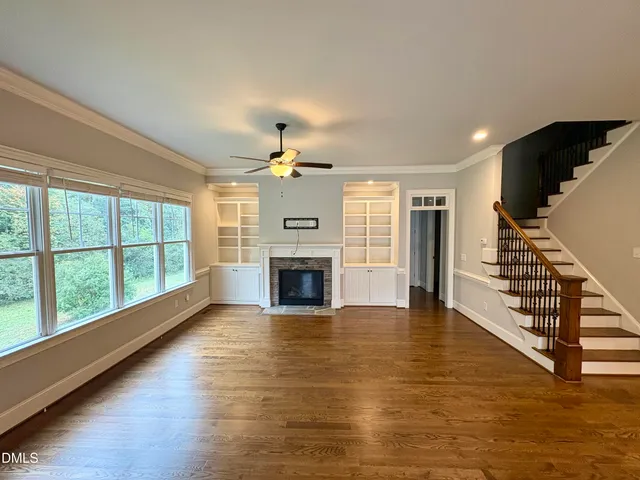 a view of a livingroom with wooden floor fireplace and a window