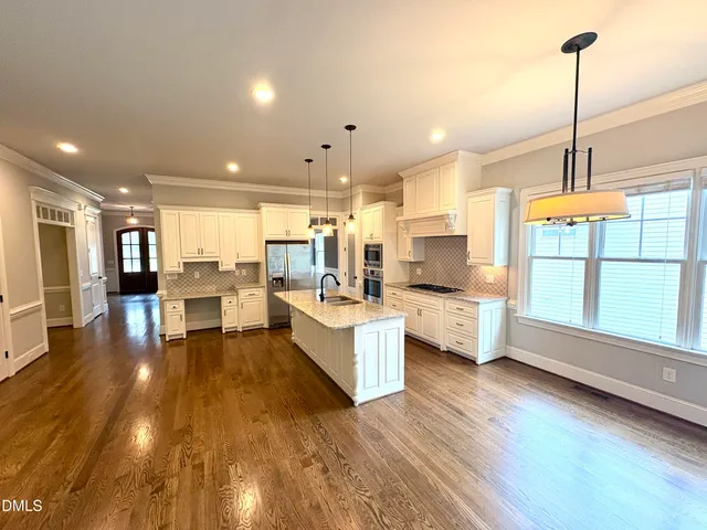 a large living room with stainless steel appliances furniture wooden floor and a large window