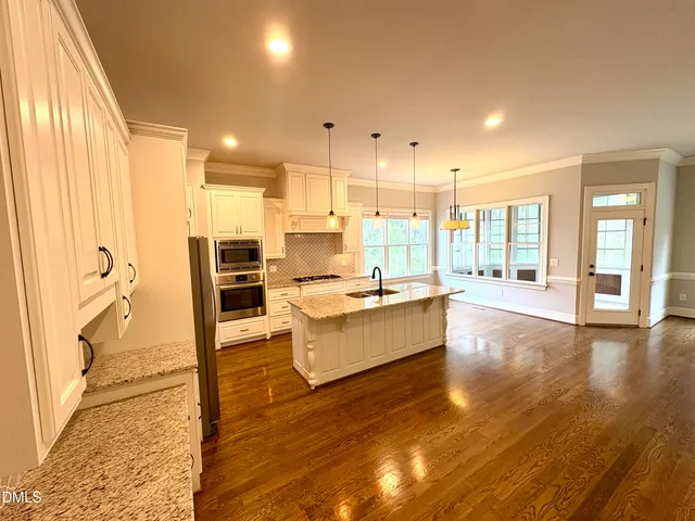 a large living room with kitchen island granite countertop wooden floor and a large window